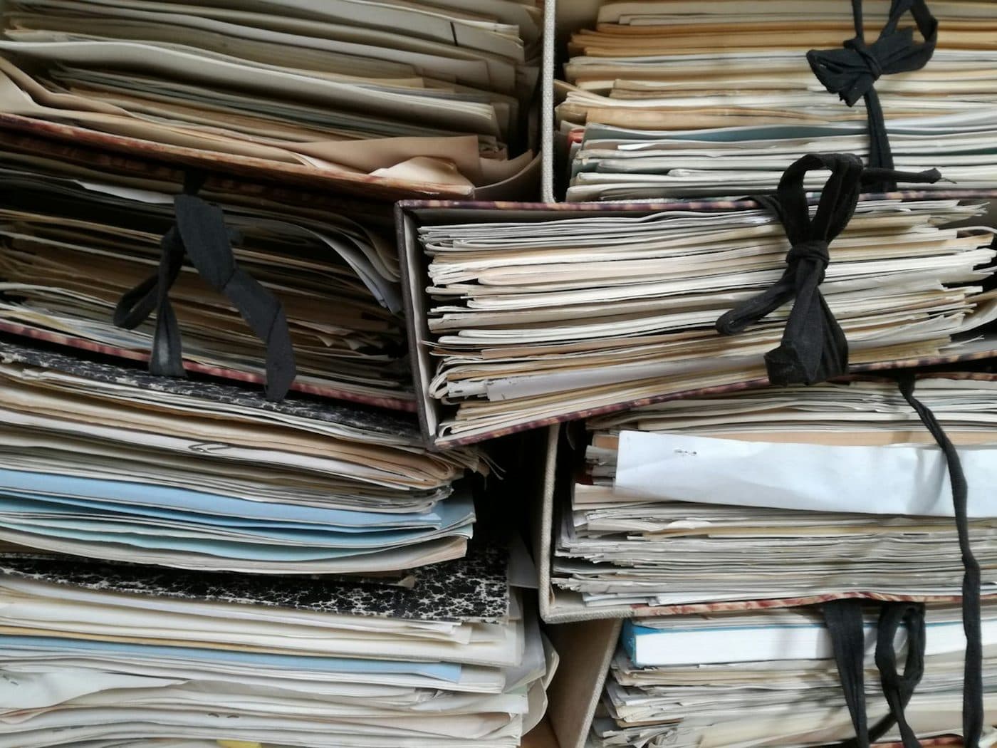 Expedientes de papel atados con cinta, apilados en el archivo de un despacho